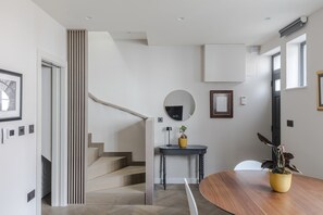 Stunning interior with a unique staircase, round mirror, and a dining table.