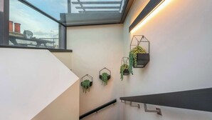 Un interno moderno con una finestra a lucernario, fioriere geometriche a parete e una scala minimalista.