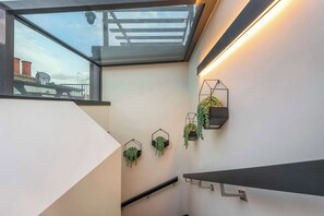 A modern interior with a skylight, geometric wall-mounted planters, and a minimalist staircase.
