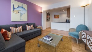 A modern living room with a grey sofa, a coffee table, and a blue armchair. - Fitzrovia Duplex · 2-Bed · Private Patio Garden (London)