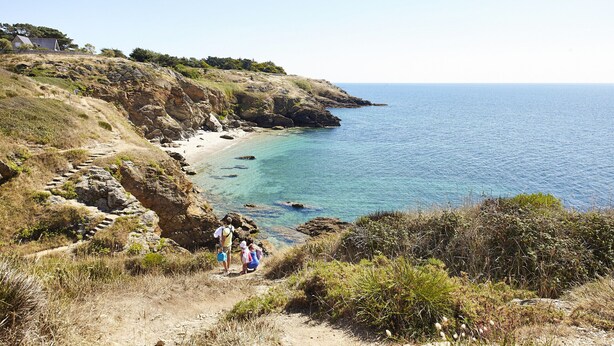 A coastal landscape with a rocky beach, clear blue sea, and a few people walking on a dirt path. - 200 m from the beach, lovely flat for 4 people (Saint-Gildas-de-Rhuys)