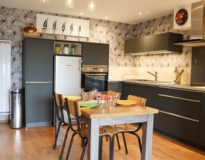 A modern kitchen with a dining area, featuring a refrigerator, oven, and stainless steel appliances. - 200 m from the beach, lovely flat for 4 people (Saint-Gildas-de-Rhuys)