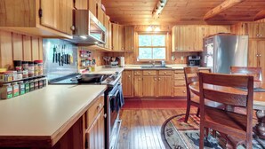 A wooden cabin-style kitchen with a stove, sink, and refrigerator. - Dog-Friendly Park Falls Cottage w/ 5 Acres & Lake (Park Falls)