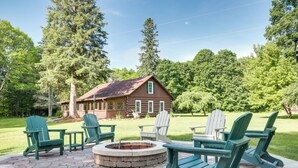A wooden cabin with a stone fire pit and Adirondack chairs in a wooded area. - Dog-Friendly Park Falls Cottage w/ 5 Acres & Lake (Park Falls)
