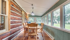 A log cabin interior with a wooden dining table and chairs, large windows, and a hanging light fixture. - Dog-Friendly Park Falls Cottage w/ 5 Acres & Lake (Park Falls)