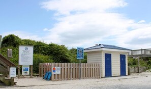 A beach access point with a wooden fence, a small building with a blue door, and informational signs. - The Treasure Chest - 3 BR/2 BA Upper Part of Duplex in the Heart of Surf City (Surf City)