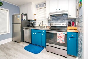 A modern kitchen with white cabinets, a stainless steel refrigerator, a dishwasher, a double oven, and a blue countertop. - The Treasure Chest - 3 BR/2 BA Upper Part of Duplex in the Heart of Surf City (Surf City)