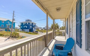 A covered porch with a railing, a blue chair, and a view of a blue house across the street. - The Treasure Chest - 3 BR/2 BA Upper Part of Duplex in the Heart of Surf City (Surf City)