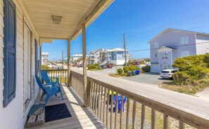 A wooden porch with blue chairs, a clear view of the street, and a residential area with houses. - The Treasure Chest - 3 BR/2 BA Upper Part of Duplex in the Heart of Surf City (Surf City)