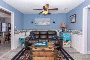 A living room with a brown leather sofa, a wooden chest, and a patterned rug. - The Treasure Chest - 3 BR/2 BA Upper Part of Duplex in the Heart of Surf City (Surf City)