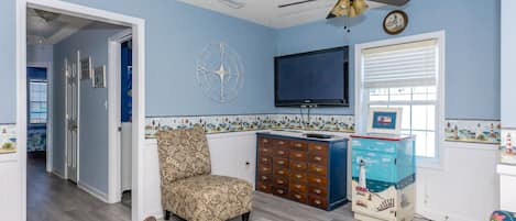 A living room with a television, a decorative compass, and a patterned chair.