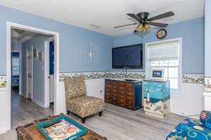 A living room with a television, a decorative compass, and a patterned chair. - The Treasure Chest - 3 BR/2 BA Upper Part of Duplex in the Heart of Surf City (Surf City)
