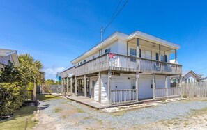 A two-story house with a balcony, a garage, and a fenced yard. - The Treasure Chest - 3 BR/2 BA Upper Part of Duplex in the Heart of Surf City (Surf City)