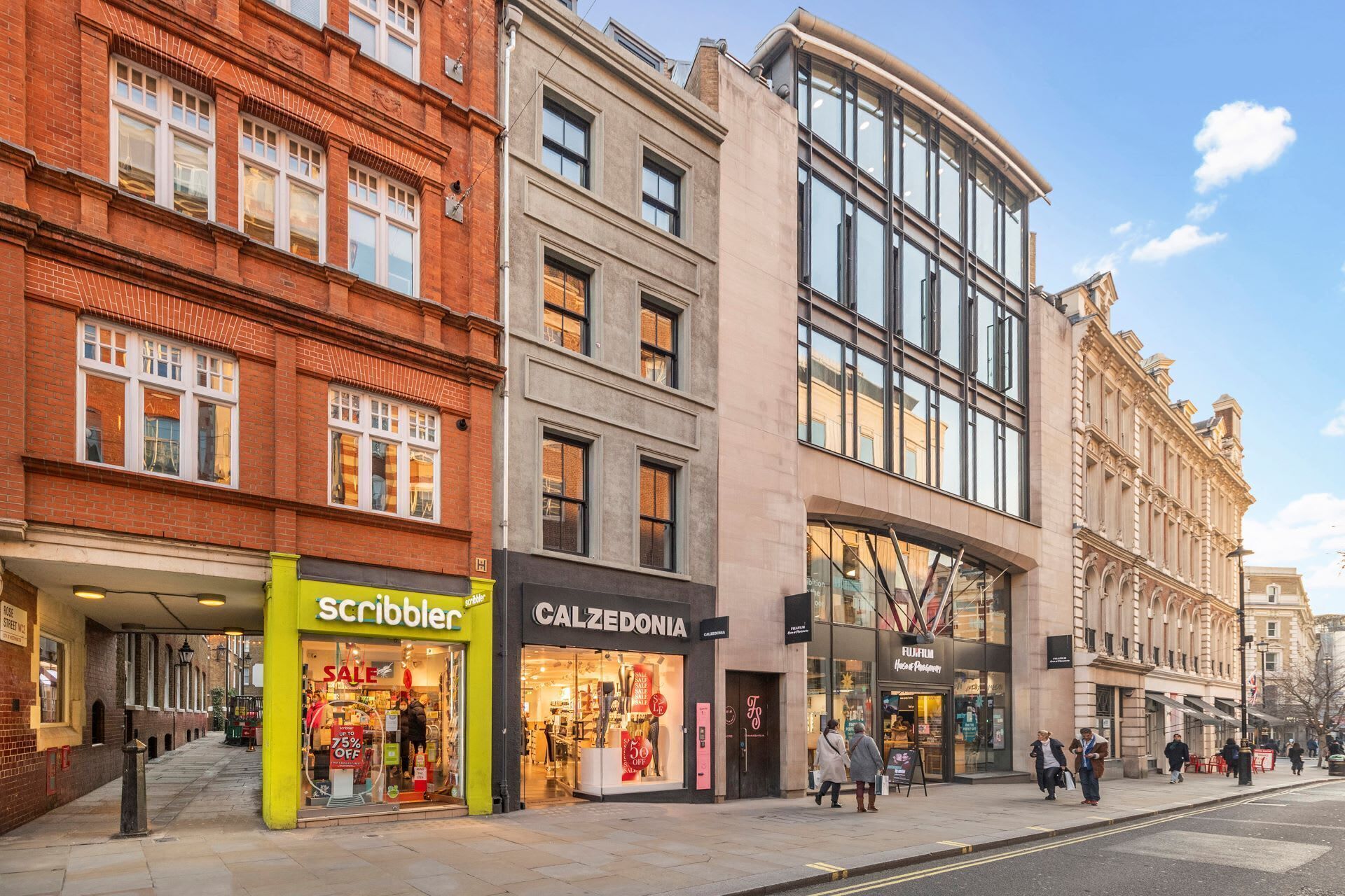 A street view with a variety of shops, including a visible store named 'scribbler' with a sale sign.