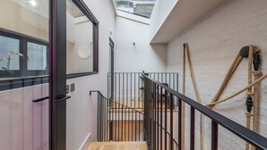 A modern interior with a wooden staircase, metal railings, and a rope installation on the wall. - Covent Garden 2-Bed Triplex · Sleeps 6 (London)