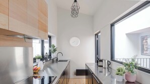 A modern kitchen with stainless steel appliances, wooden cabinets, a black countertop, and a window with a view. - Covent Garden 2-Bed Triplex · Sleeps 6 (London)
