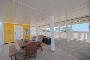A covered outdoor area with a table and chairs, a door, and a view of the beach. - Welcome to the “Pot O’ Gold” at the end of the rainbow! (St. George Island)
