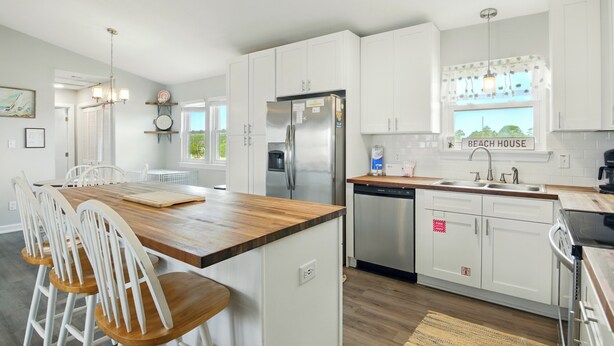 A modern kitchen with white cabinets, stainless steel appliances, and a wooden island. - Welcome to the “Pot O’ Gold” at the end of the rainbow! (St. George Island)