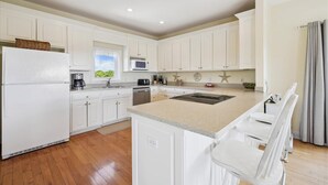 A modern kitchen with white cabinetry, a central island, and a breakfast bar.