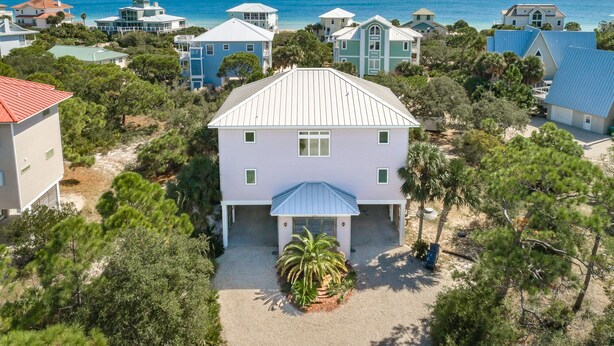 A coastal property with a central white house, surrounded by other buildings, and a view of the ocean.