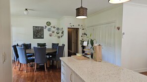 A dining area with a wooden table and chairs, a kitchen counter, and a door leading to another room.
