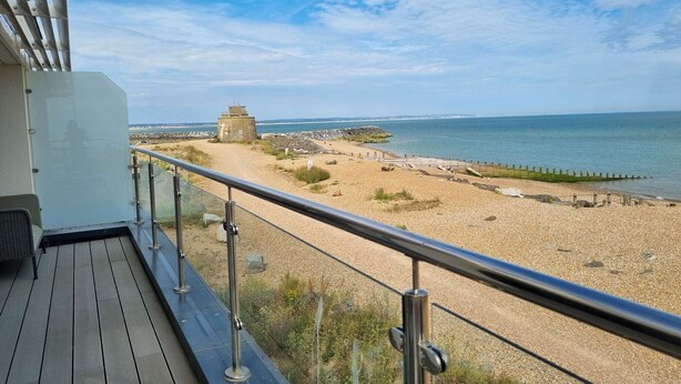 A deck with a railing overlooking a pebble beach and the sea. - White Point beach house (Eastbourne)