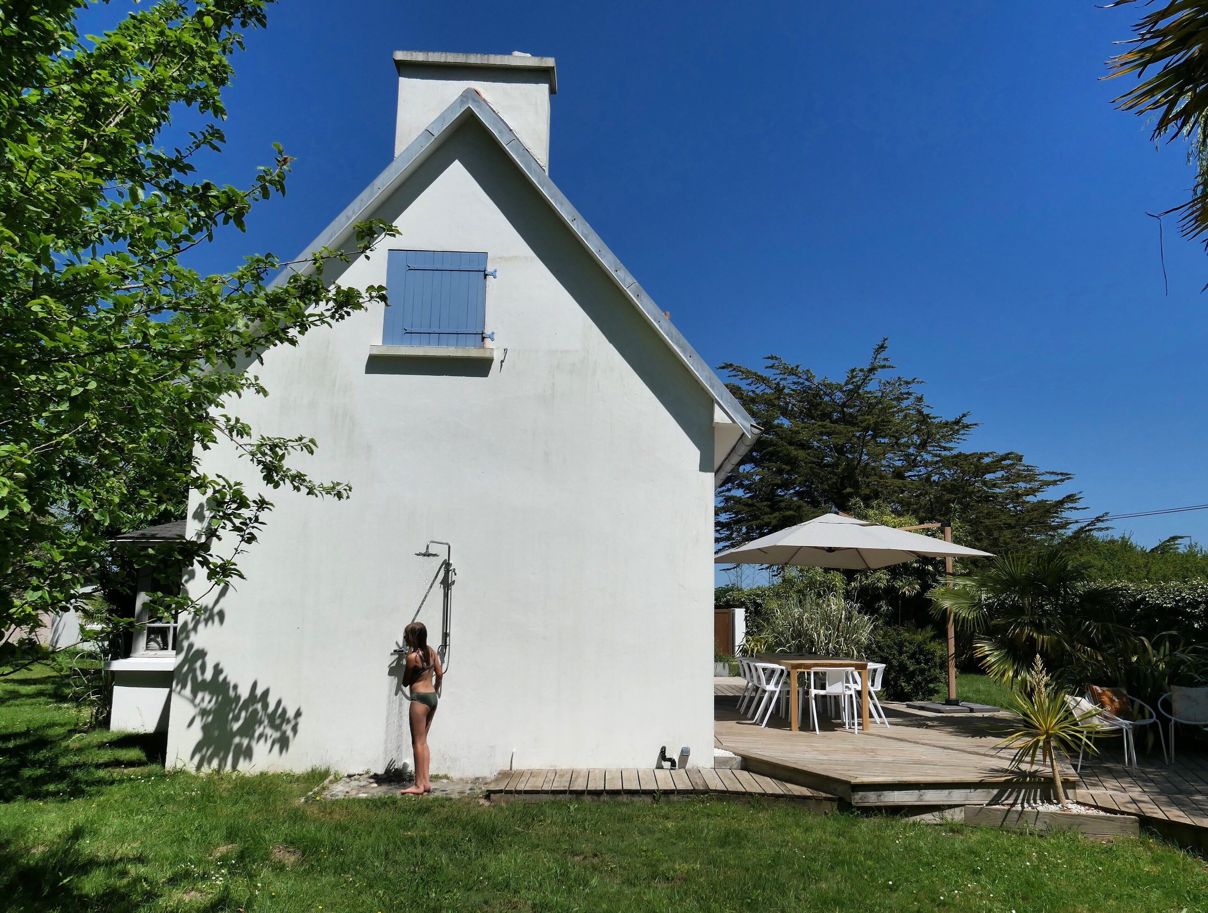 A white building with a blue window and a small porch area with outdoor furniture.