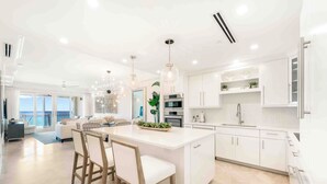 Uma cozinha moderna com armários brancos, uma ilha central e iluminação pendente.