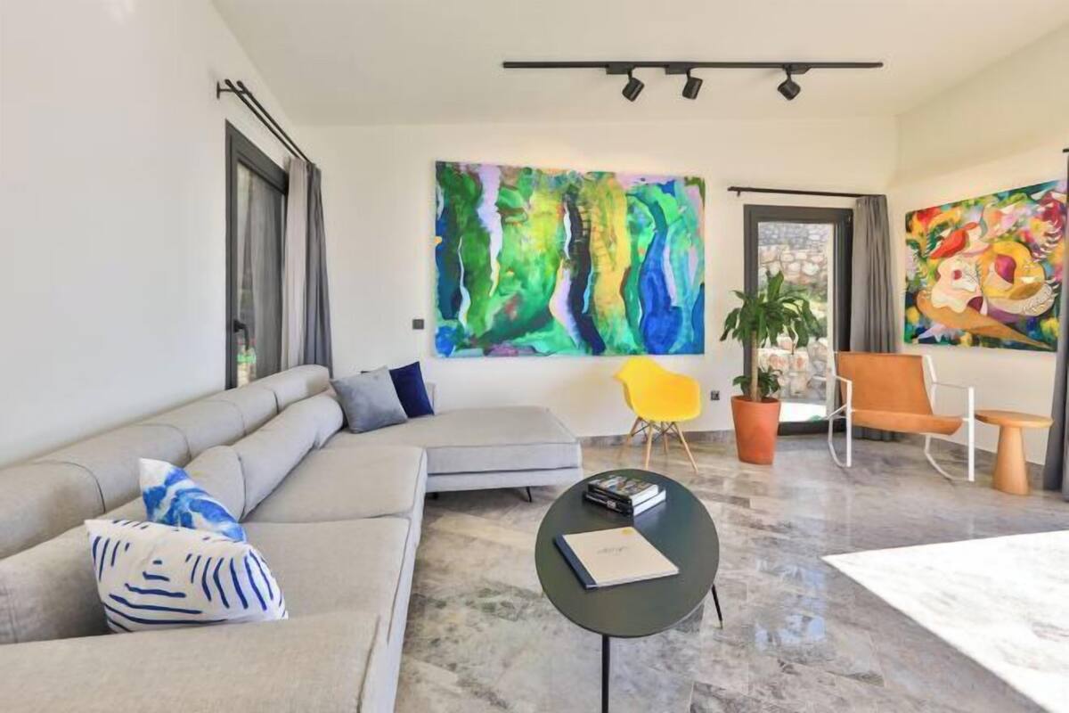 A modern living room with a sectional sofa, a small round table, and two chairs.