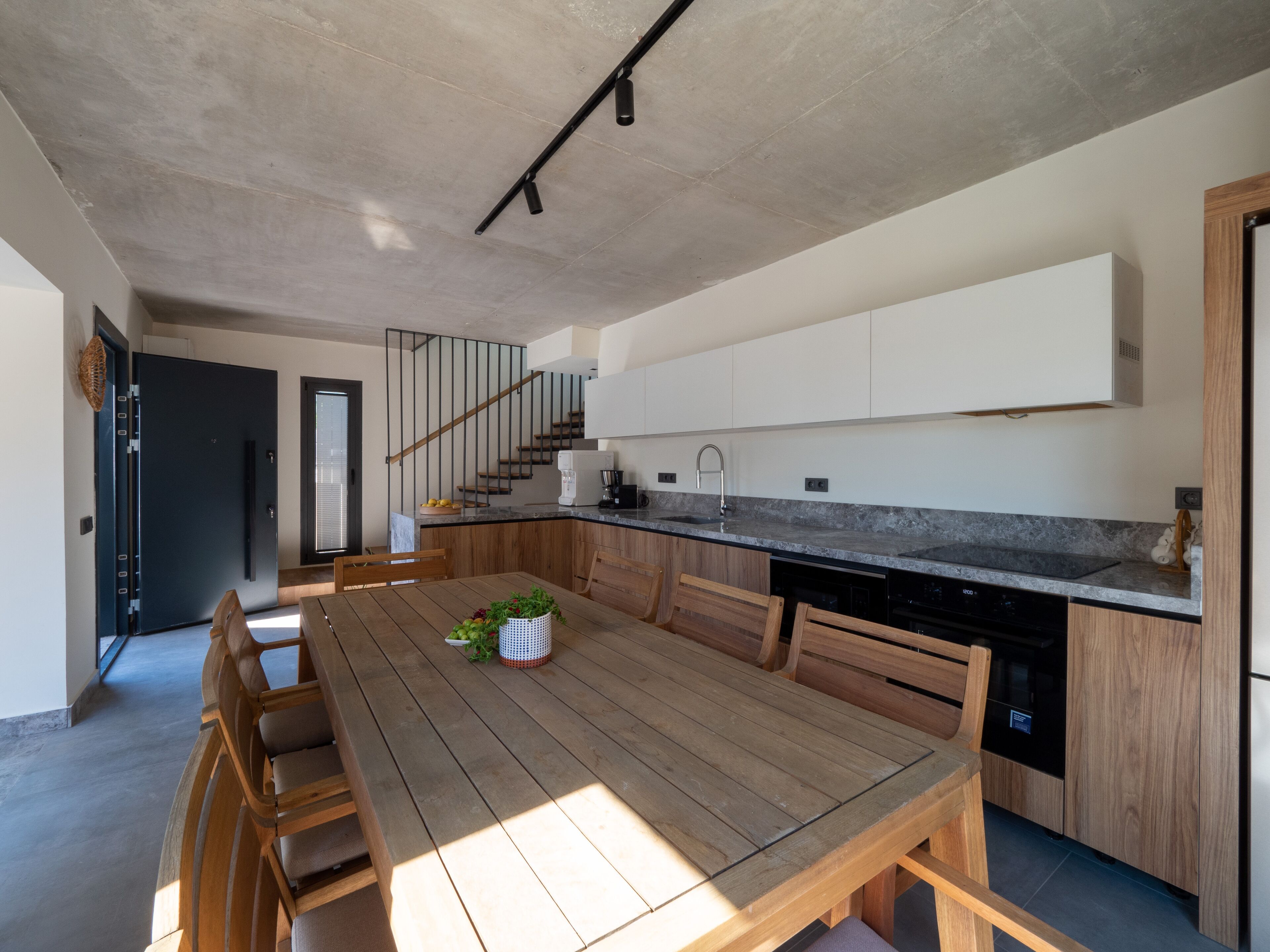 A modern kitchen with wooden cabinetry, a built-in dishwasher, and a large island with seating.