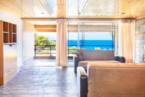 Un balcon spacieux avec vue sur la mer, un canapé et un plafond en bois.