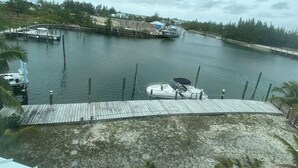 A marina with docked boats, a wooden dock, and a view of buildings across the water. - Starboard House:  Lots of space in Canalfront Home close to beach (Treasure Cay)
