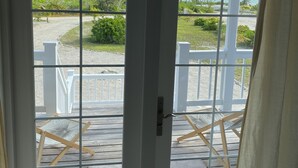 A glass door with a view of a wooden deck and outdoor furniture. - Starboard House:  Lots of space in Canalfront Home close to beach (Treasure Cay)