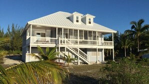 A two-story house with a balcony and a covered porch. - Starboard House:  Lots of space in Canalfront Home close to beach (Treasure Cay)