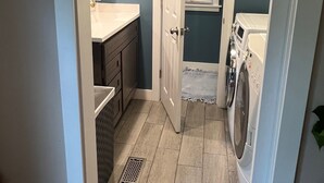 A compact laundry room with a washing machine, a sink, and a towel rack. - Cozy Cottage near UNCW, Central Location to All! (Wilmington)