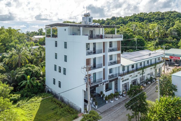 A multi-story hotel with a flat roof, balconies, and a sign indicating it is a 'leaf hotel'.