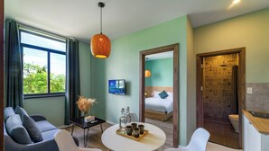 Quarto de hotel moderno com sofá, mesa de jantar, cadeiras, televisão, cama e banheiro.