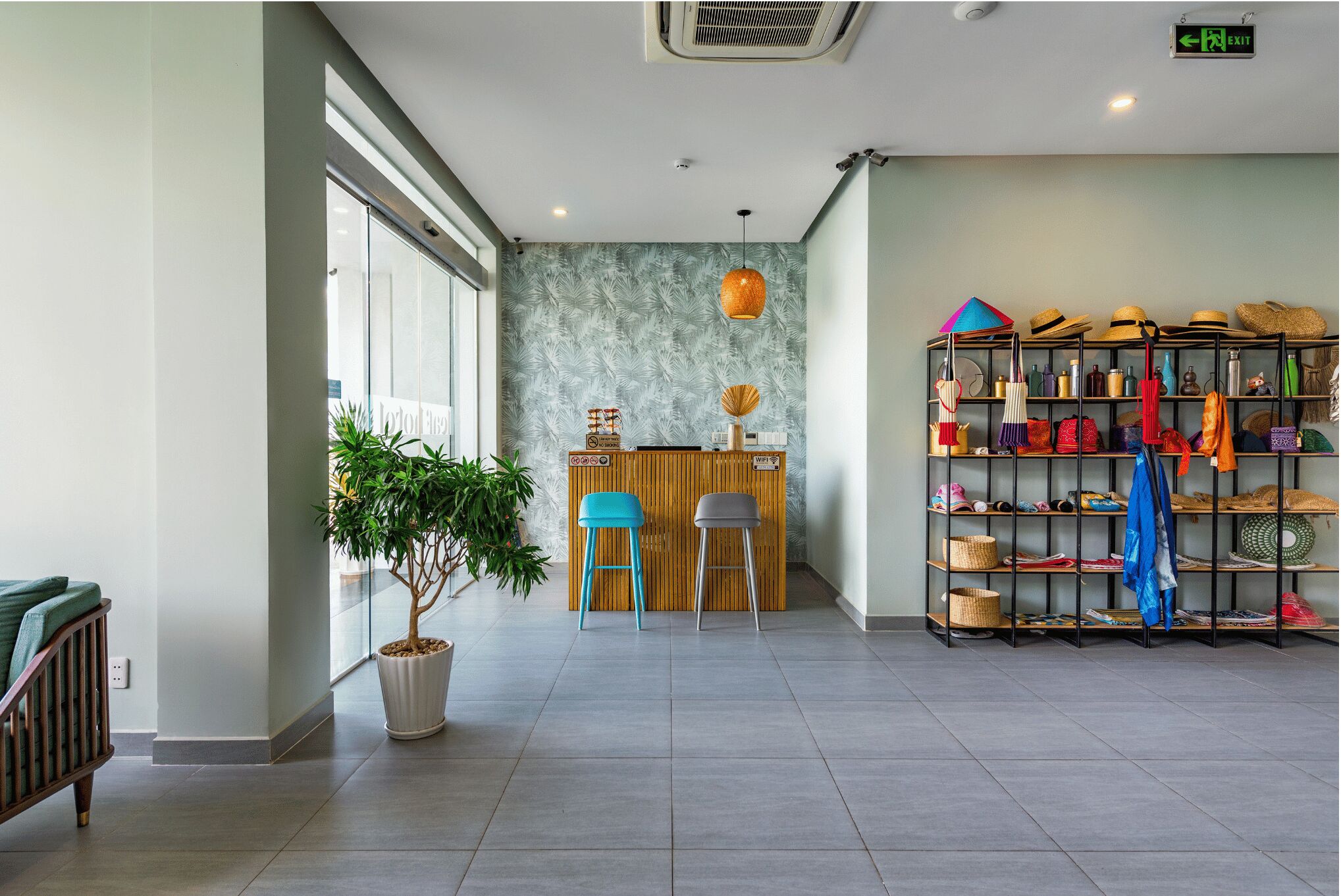 Zona de recepción con un escritorio de madera, dos sillas, una planta en maceta y un zapatero con varios objetos.