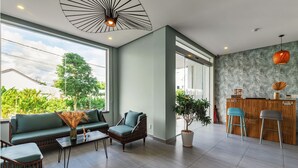 Uma sala de estar moderna com sofá, poltronas, mesa de centro e área de jantar com banquetas.