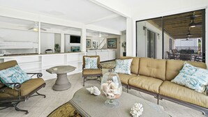 A spacious living room with a large sofa, armchairs, a coffee table, and a dining area with a table and chairs.