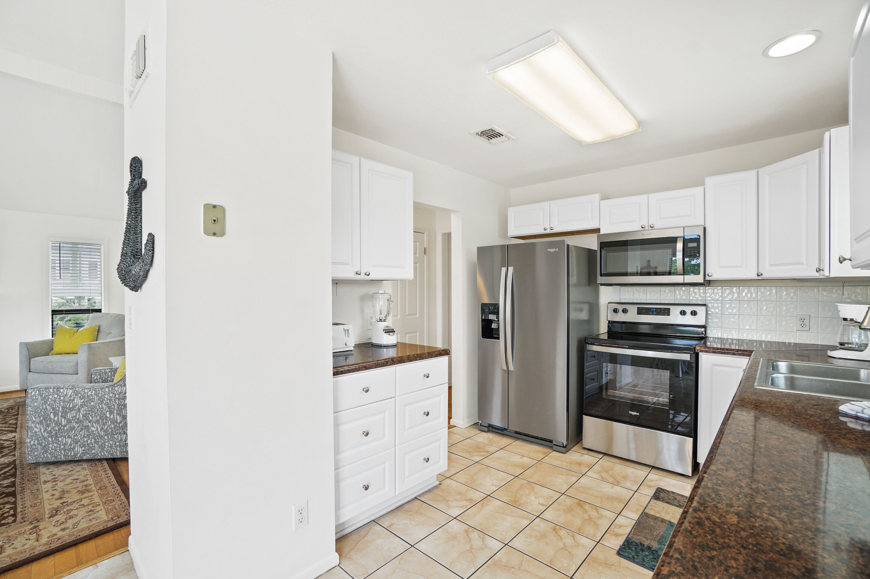 A modern kitchen with white cabinets, stainless steel appliances, and a granite countertop.