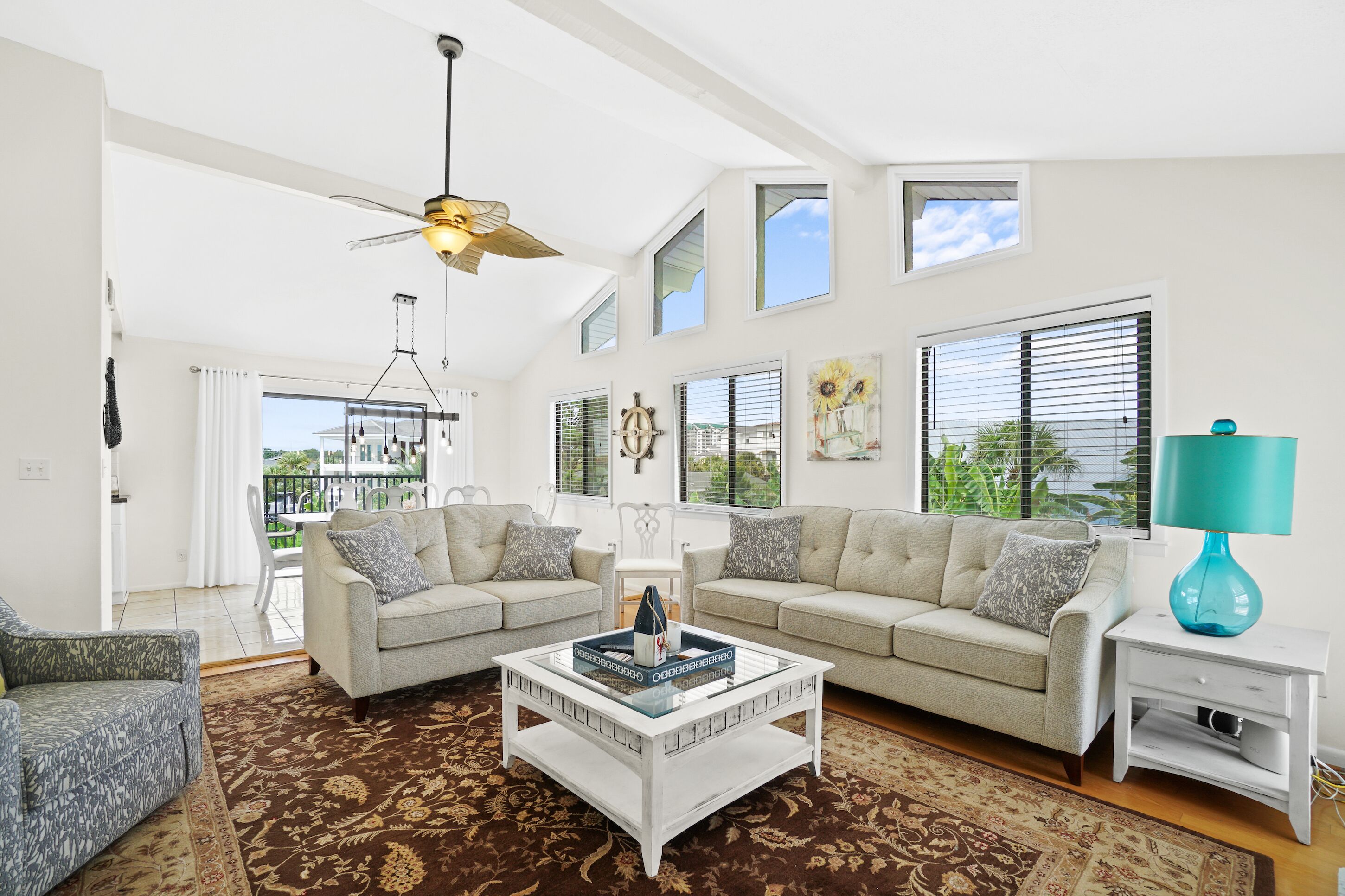 A spacious living room with a high ceiling, two sofas, a coffee table, and a ceiling fan.