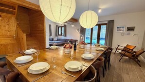 A dining area with a wooden table set for four, surrounded by wooden chairs. There are two hanging paper lanterns above the table. - Chalet les Ecrins - 230m2 ✨ Sauna - Swimmingpool - Garden ✨  (Vénosc, Les Deux Alpes)
