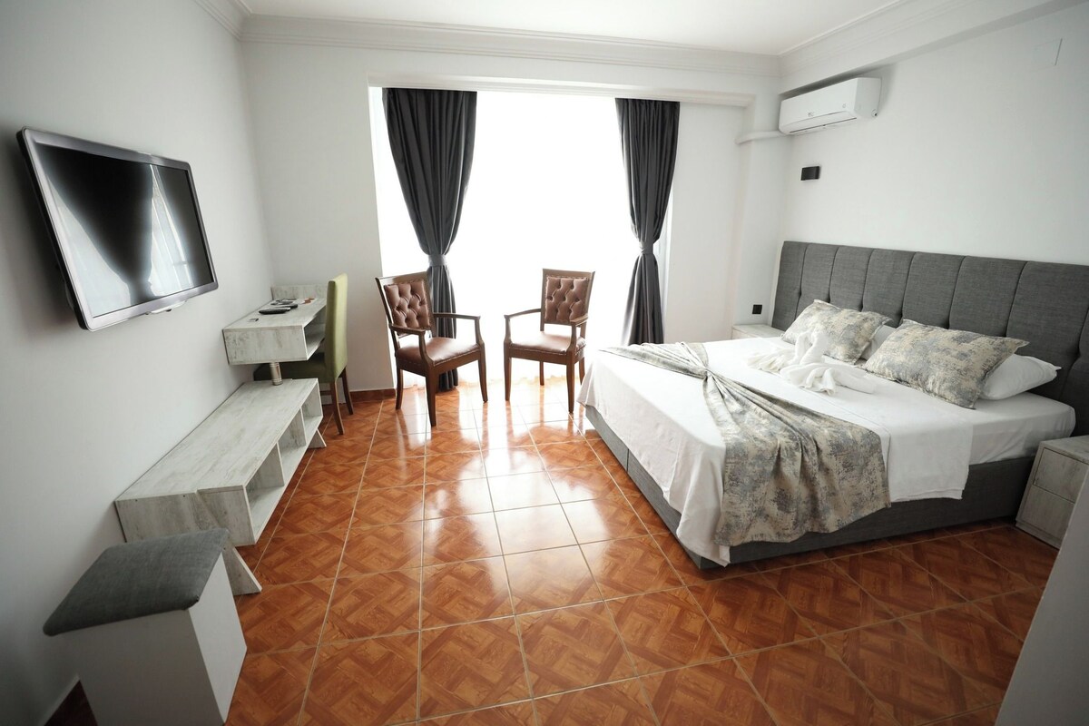 Una habitación de hotel con una cama, televisión, escritorio y dos sillas.