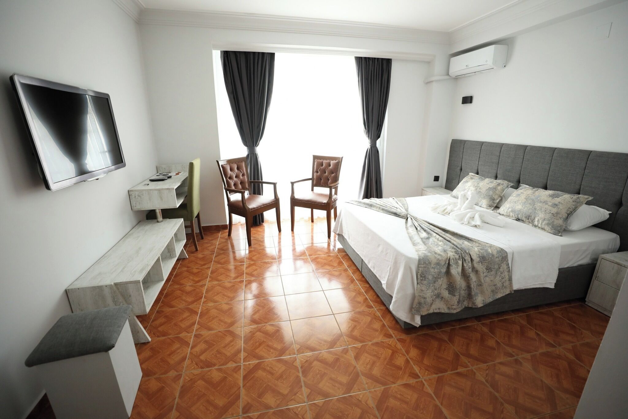 A hotel room with a bed, a TV, a desk, and two chairs.