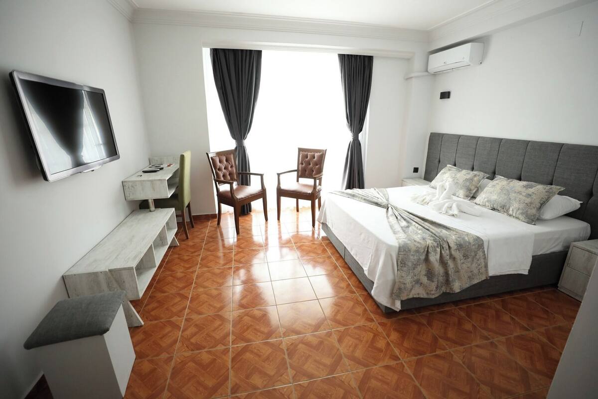 A hotel room with a bed, a TV, a desk, and two chairs.