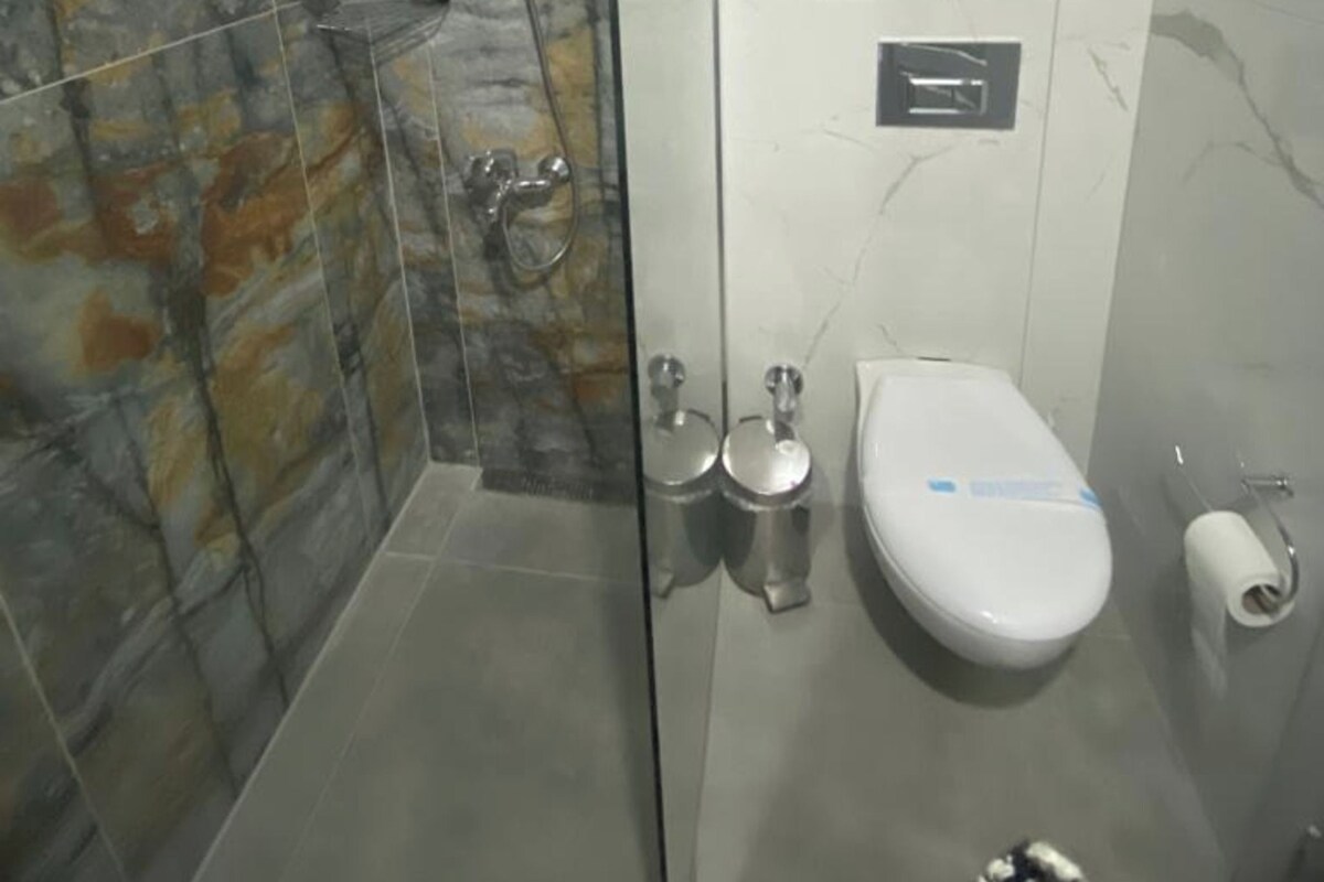 Un baño moderno con ducha de vidrio, inodoro y pared de mármol.