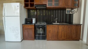 A compact kitchen with a refrigerator, microwave, stove, oven, and wooden cabinets. - Royani 1-Bedroom Private Pool Villa (Gianyar)