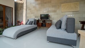 A modern living room with two sofas, a TV, and a wooden entertainment unit. - Royani 1-Bedroom Private Pool Villa (Gianyar)