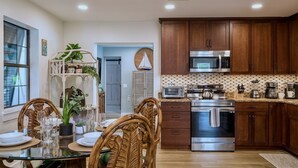Una cocina moderna con armarios de madera, electrodomésticos de acero inoxidable y un comedor con mesa de vidrio y sillas de mimbre.